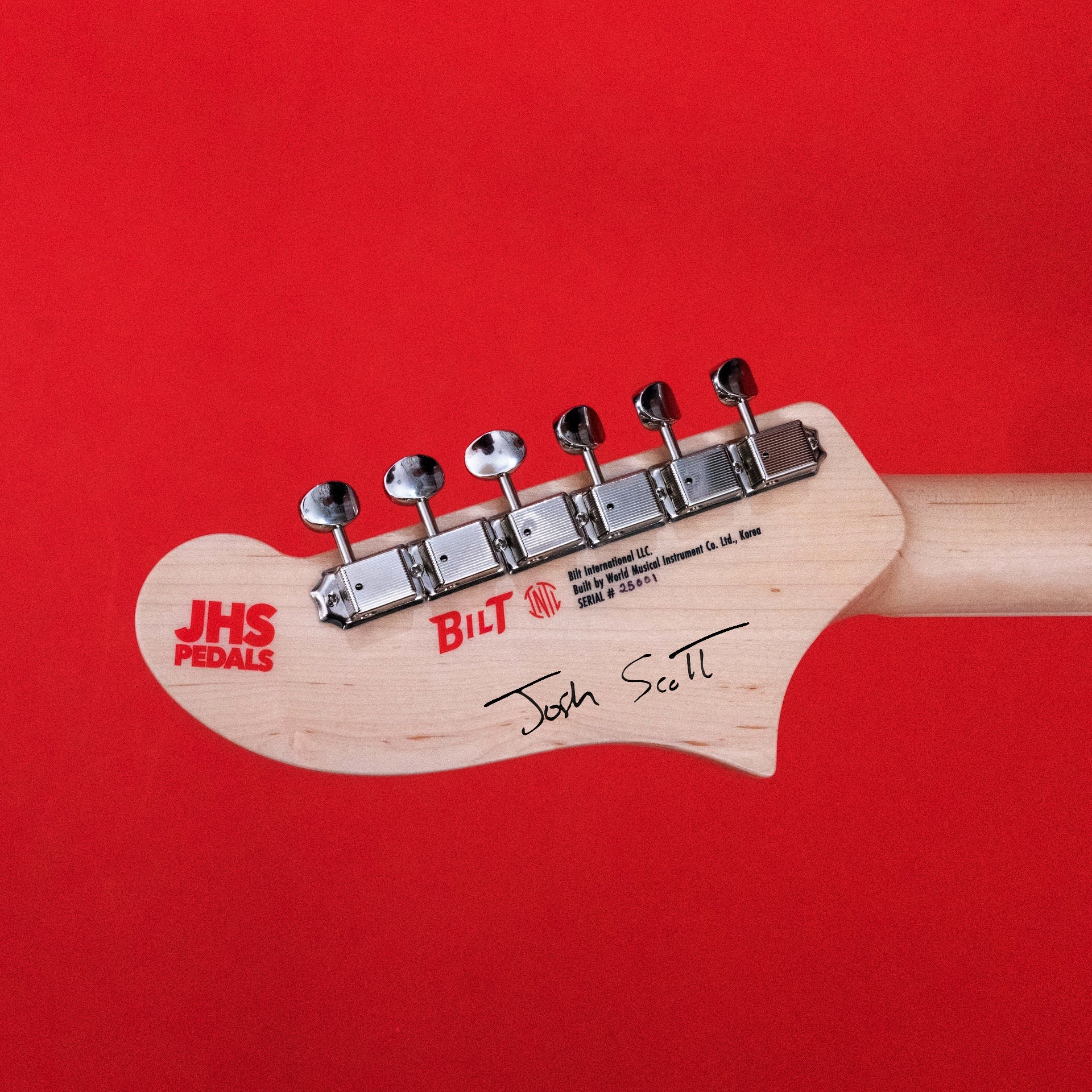Guitar headstock with 'JHS Pedals' and 'Bilt' branding on a red background