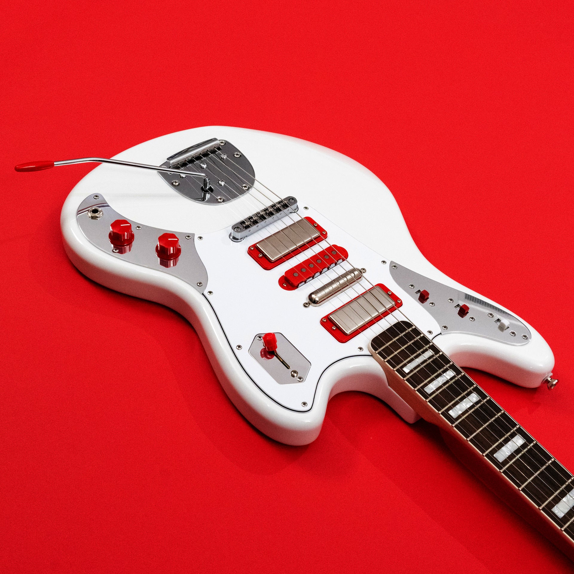 White JHS Relevator electric guitar body detail with red accents on a red background