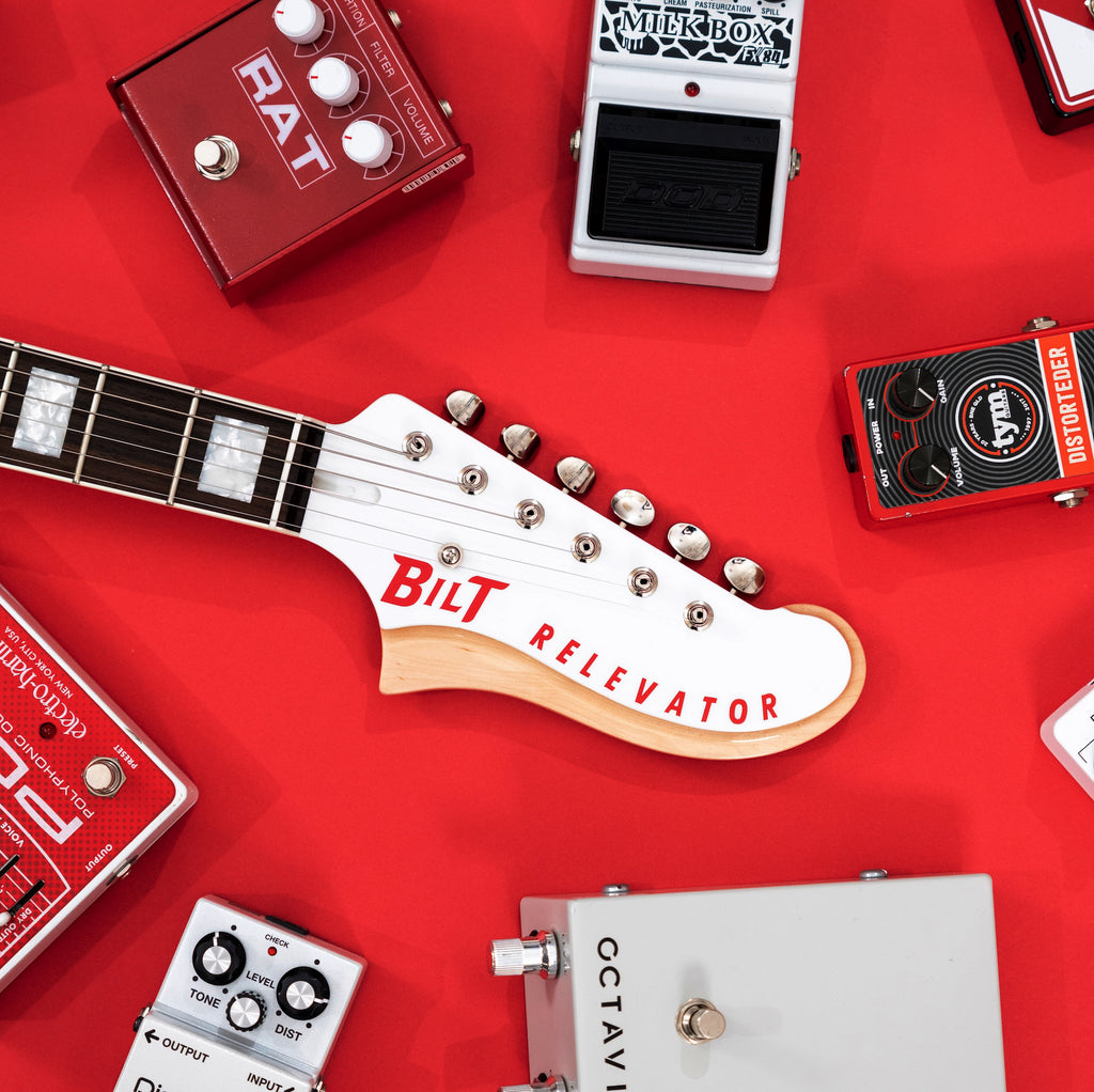 Headstock with 'Bilt Relevator' on a red background with guitar effects pedals.